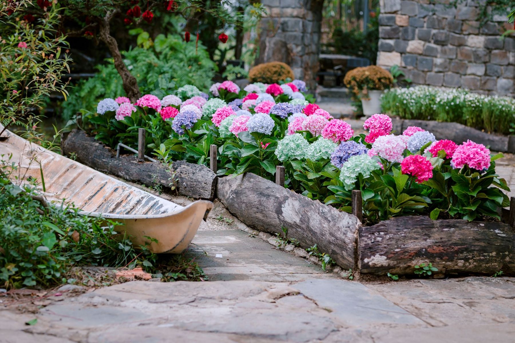 A planted landscaping bed with flowers beside a stone walkway